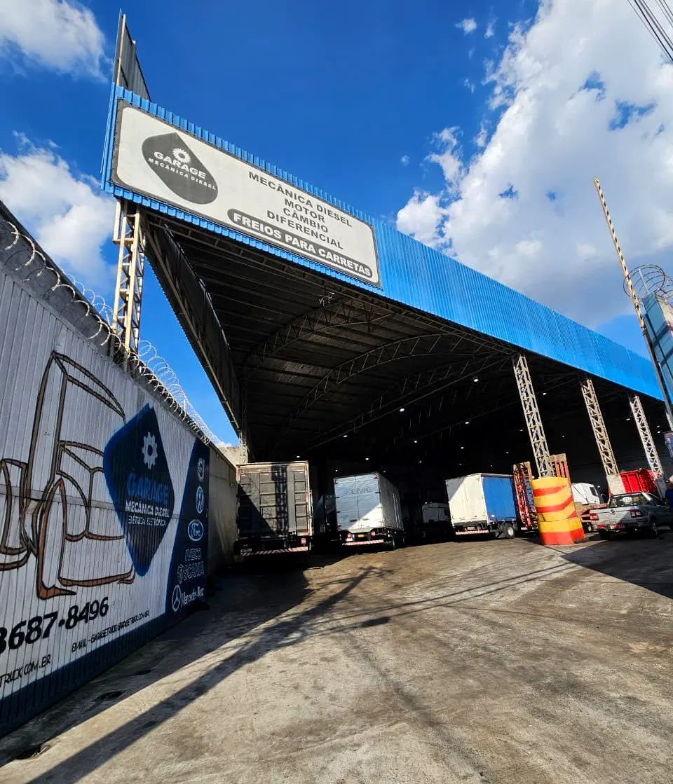 Entrada da sede da Garage Truck Center na Av. dos Remédios, com a cobertura azul e caminhões no pátio